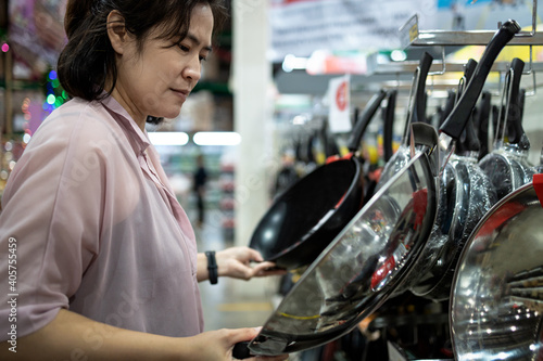 Fényképezés Female housewife or cook choosing teflon frying pan or deciding to buy steel fry