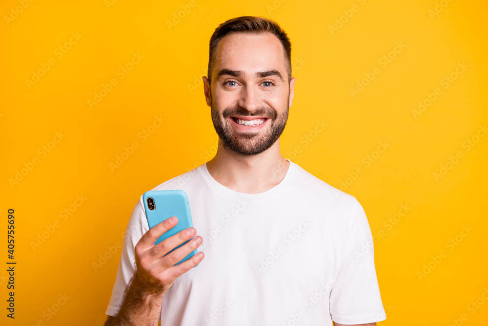 Portrait of optimistic guy hold telephone wear white t-shirt isolated on vibrant yellow color background Portrait of optimistic guy hold telephone wear white t-shirt isolated on vibrant yellow color background