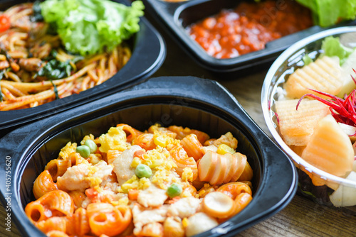 Service food order online delivery Spaghetti italian pasta macaroni cheese with sausage and fruit on food box, food delivery in take away boxes package on wooden table at home.