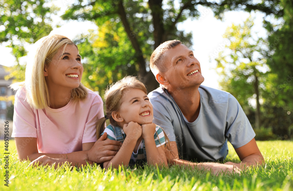 Fototapeta premium Happy parents with their child having fun on green grass. Spending time in nature