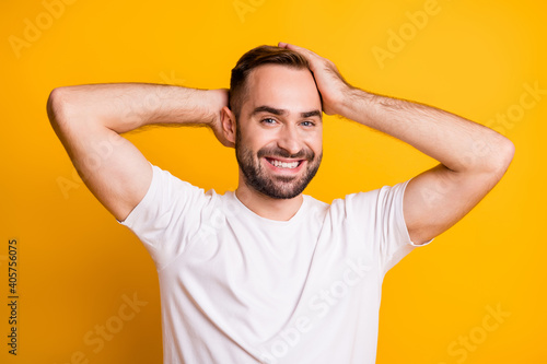 Portrait of optimistic guy touch hair wear grey t-shirt isolated on vibrant yellow color background