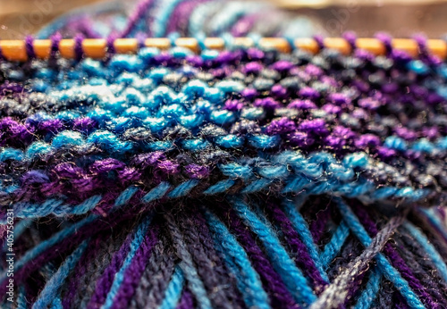 Knitting on wooden knitting needles from violet blue purple yarn close-up. Hobby, homemade, abstract background © Lena_viridis