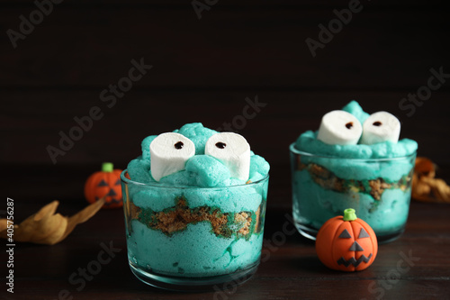 Delicious desserts decorated as monsters on wooden table. Halloween treat © New Africa