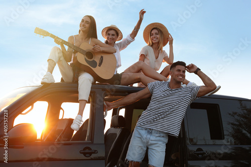 Happy friends with guitar outdoors at sunset. Summer trip © New Africa