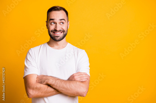 Portrait of attractive cheerful bearded curious guy folded arms copy space thinking isolated over bright yellow color background