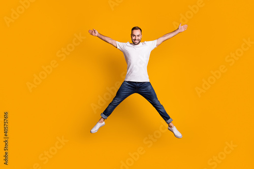 Full length body size view of nice carefree cheerful guy jumping having fun isolated over bright yellow color background