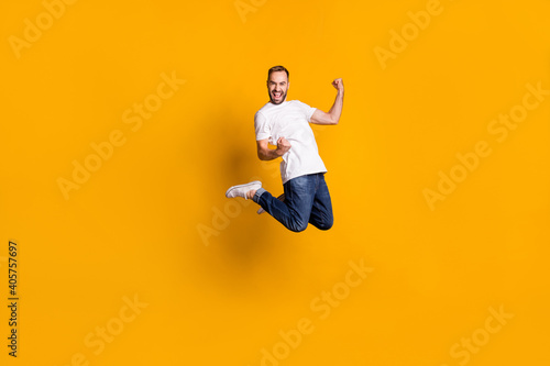 Full length body size view of nice lucky cheerful guy jumping rejoicing isolated over bright yellow color background © deagreez