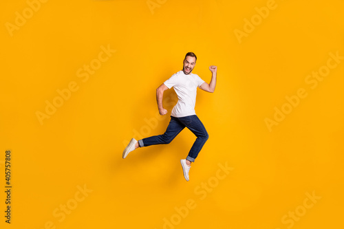 Full length body size photo of jumping man wearing casual clothes isolated bright yellow color background