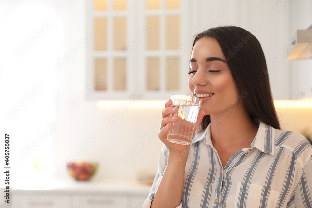 Young woman drinking pure water from glass in kitchen. Space for text Young woman drinking pure water from glass in kitchen. Space for text