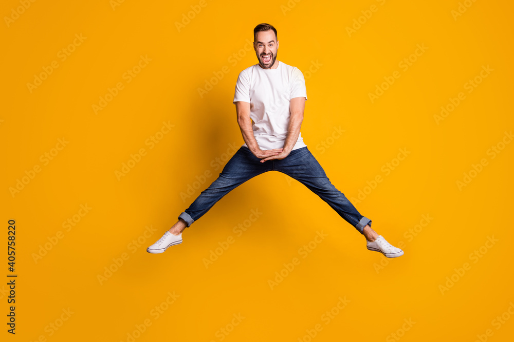 Full length body size photo of cheerful happy jumping man childish playful laughing isolated vivid yellow color background