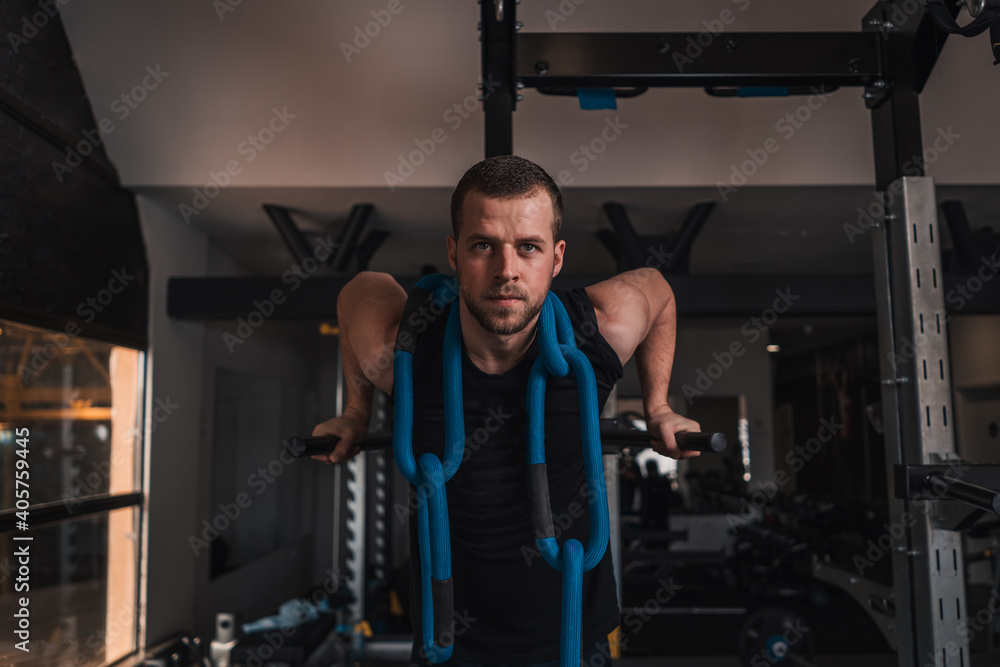 Fit man workout out arms on dips horizontal bars training triceps and biceps doing push ups indoors in gym Fit man workout out arms on dips horizontal bars training triceps and biceps doing push ups indoors in gym