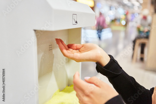 Kunde beim Hände desinfizieren am Supermarkt Eingang photo