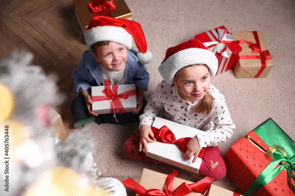 Cute little children with Christmas gifts on floor at home, above view