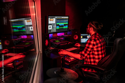 Foto Young producer with beard is working on the mixer with audio and track in the record studio