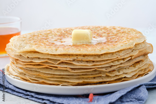 Crepes, thin pancakes with honey and butter on a white plate. Close up.