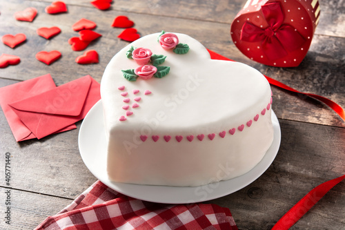 Heart cake for St. Valentine's Day, Mother's Day, or Birthday, decorated with roses and pink sugar hearts on wooden table.