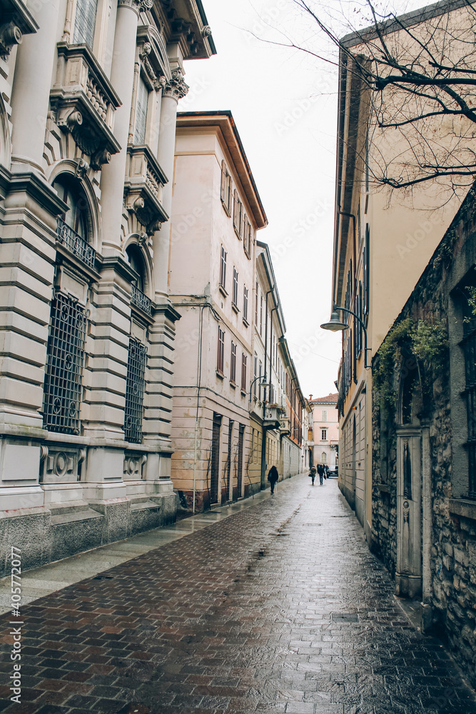 Empty medieval ancient streets in Como city, Lombardy, Italy. Vertical image of cityview with historical buildins and villas around in gloomy winter day. Selective focus