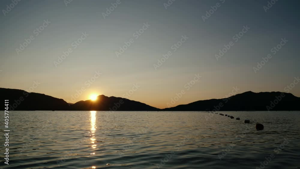 Timelapse of seascape with yachts and sun rising over the hills. Sunrise over sea and mountains. Ships against backdrop of rocky shores. Ideal destination concept for summer travel and vacation Timelapse of seascape with yachts and sun rising over the hills. Sunrise over sea and mountains. Ships against backdrop of rocky shores. Ideal destination concept for summer travel and vacation