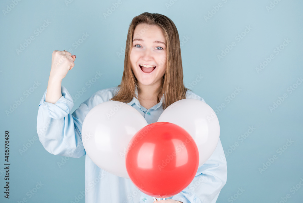 Smiling woman holding balloon and looking at camera over blue background. Smiling woman holding balloon and looking at camera over blue background.
