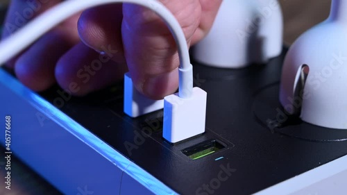 Close-up macro of a male hand unplugging cables from the power outlet. Modern convenient multi-port usb charger for devices. 