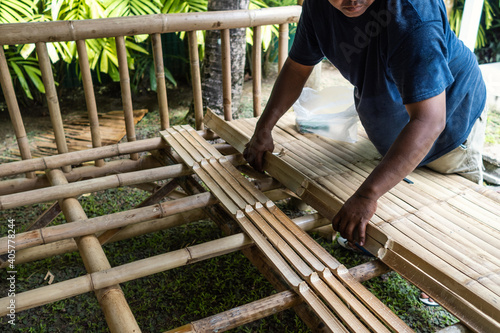 Man neatly doing flooring by using bamboo canes. Bamboo constructed building details.