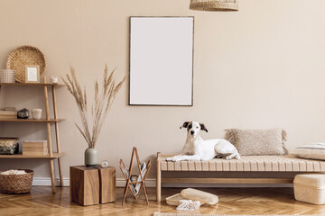 Boho composition of living room with furnitures, mock up painting, rattan decoration, bamboo shelf with elegant personal accessories. Beautiful dog lying on the chaise longue. Home decor Template.