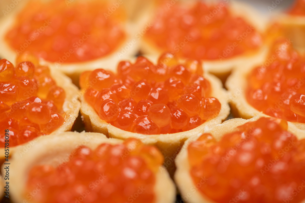 Tartlets with salmon caviar on a platter. Close-up, selective focus. Tartlets with salmon caviar on a platter. Close-up, selective focus.