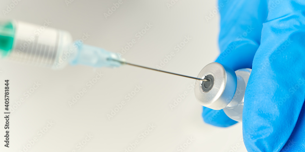 Fototapeta premium doctor hands injecting a syringe needle into a small bottle with a vaccine or drug assign virus or flu.