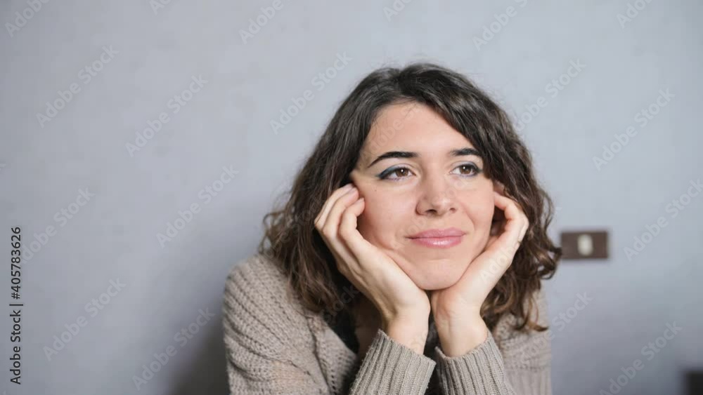 young woman portrait sitting at desk resting chin on hands while looking out the window with smily relaxed face. young woman portrait sitting at desk resting chin on hands while looking out the window with smily relaxed face.