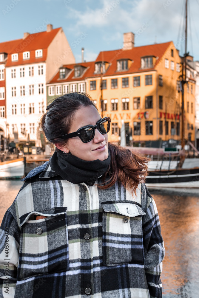 woman with sunglasses wearing warm clothes in a city on a sunny day