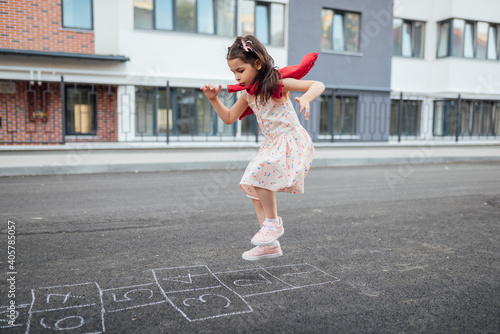 Принти на полотні Full view of little girl playing hopscotch with her mother on playground outdoors
