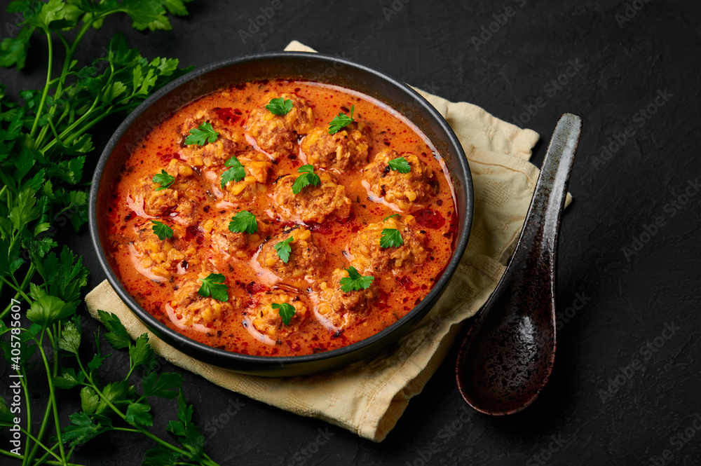 Sulu Kofte in black bowl on dark slate table top. Turkish cuisine soup dish with beef meatballs and gravy. Traditional food. Sulu Kofte in black bowl on dark slate table top. Turkish cuisine soup dish with beef meatballs and gravy. Traditional food.