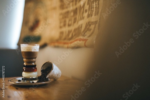 Café preparado. Bebida de café asiático sobre mesa de cafetería. Capas de café, leche condensada, licor y crema de diferentes colores. Vaso de cristal con café.