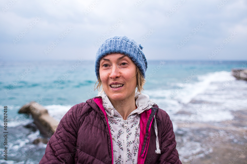 Portrait of a smiling girl in a knitted hat while walking along the sea coast Portrait of a smiling girl in a knitted hat while walking along the sea coast