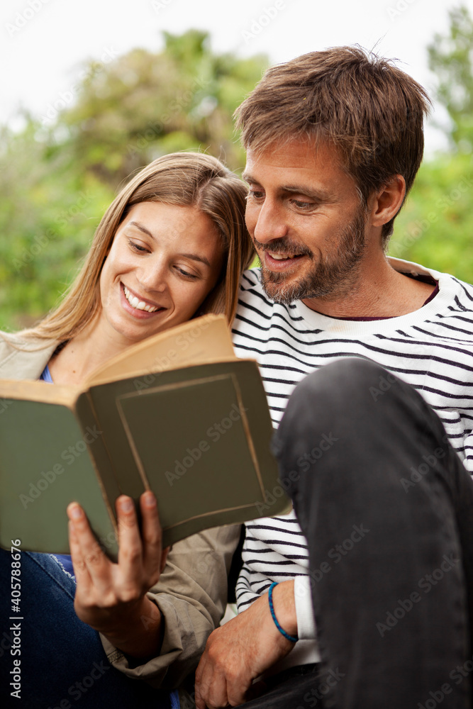 Couple reading book while sitting on bench Couple reading book while sitting on bench
