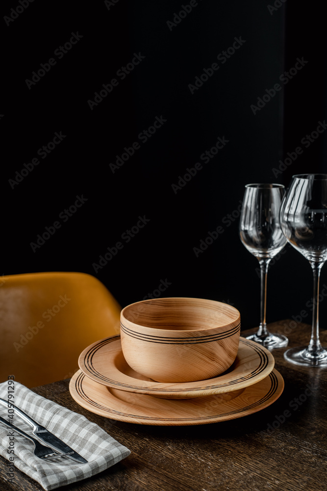 Wooden plates and glass goblets served on table on black background Wooden plates and glass goblets served on table on black background