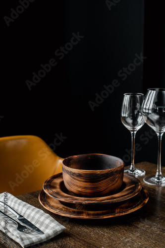 Wooden plates and glass goblets served on table on black background