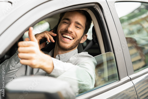 Young man showing thumbs up sign in car photo