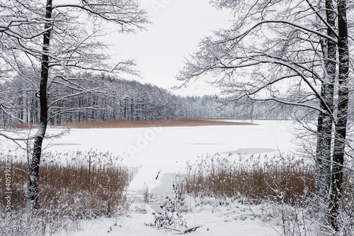 Stara kładka nad mazurskim jeziorem w zimowej śnieżnej scenerii © Ianu Arius