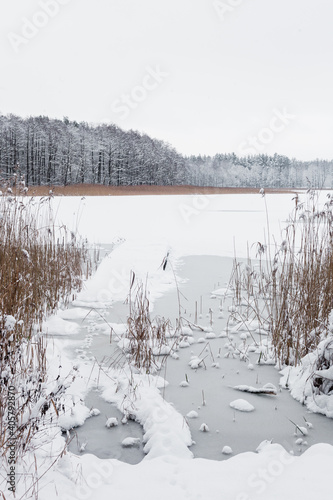 Fototapeta Naklejka Na Ścianę i Meble -  Stara kładka nad mazurskim jeziorem w zimowej śnieżnej scenerii