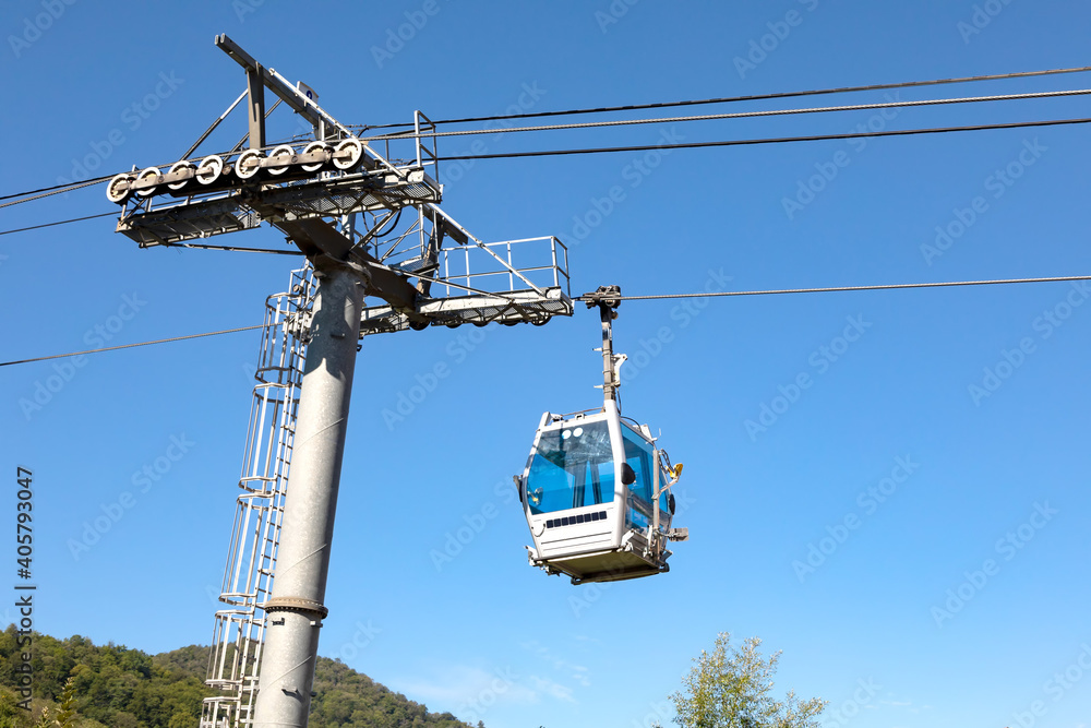 Support of the cable car and the closed cabin against the background of the sky and mountains