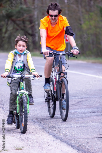 dad and son riding bicycles on country road, family workout