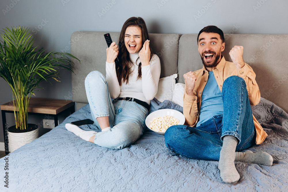 Omg what is it. Sweet young couple has quarantine free time watch movie impressed surprised unexpected thriller movie ending hold big pop corn box sit sofa in house indoors Omg what is it. Sweet young couple has quarantine free time watch movie impressed surprised unexpected thriller movie ending hold big pop corn box sit sofa in house indoors