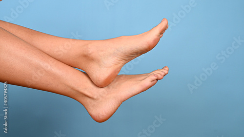 Close-up of naked female legs on blue background with copy space. Concept of pedicure, laser hair removal, foot and foot skin care © Tatsiana
