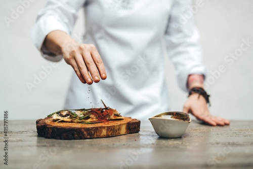 Chef sazonando un plato. Manos de cocinero aderezando. Comida gourmet. Cocinero profesional usando especias.