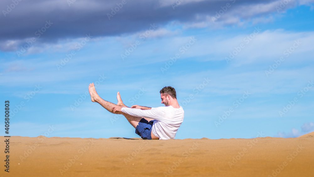 Young man falling and laughing on the sand in dunes in Gran Canaria Young man falling and laughing on the sand in dunes in Gran Canaria