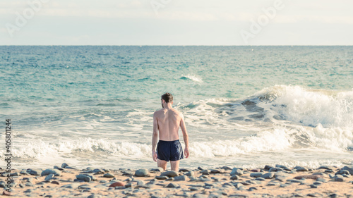 Athletic young man walking on a beach in Gran Canaria during Covid after a swim in Atlantic Ocean