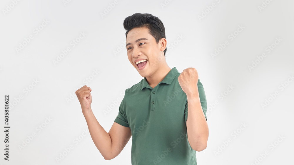 Happy excited young Asian man raising his fists doing yes gesture celebrating success Happy excited young Asian man raising his fists doing yes gesture celebrating success