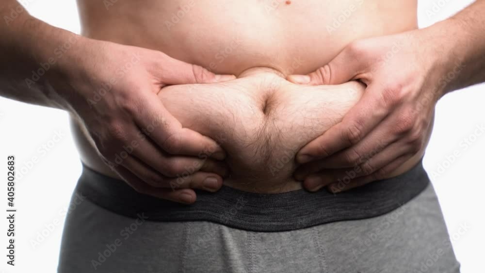 Close-up, male stomach, overweight. Young man with a naked fat belly shakes fat folds on his stomach, obesity, health, beer belly Close-up, male stomach, overweight. Young man with a naked fat belly shakes fat folds on his stomach, obesity, health, beer belly