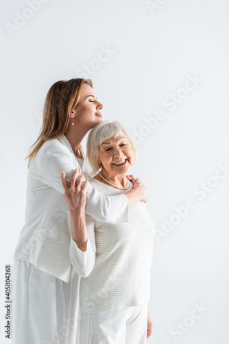 happy daughter embracing senior mother with grey hair isolated on white